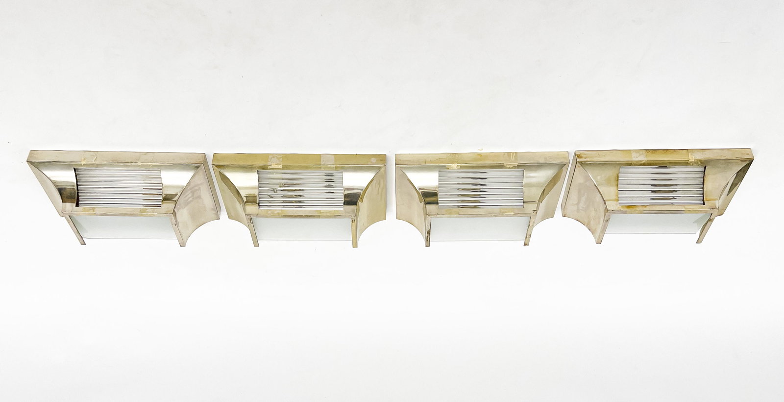 Four Art Deco Style Chrome And Glass Sconces: Lot 93 Four Art Deco Style Chrome And Glass Sconces of inverted bell form with single light behind stacks of glass tube panels, unsigned 3 1/2 x 11 7/8 x 5 7/8 inches Provenance: Property from the Col