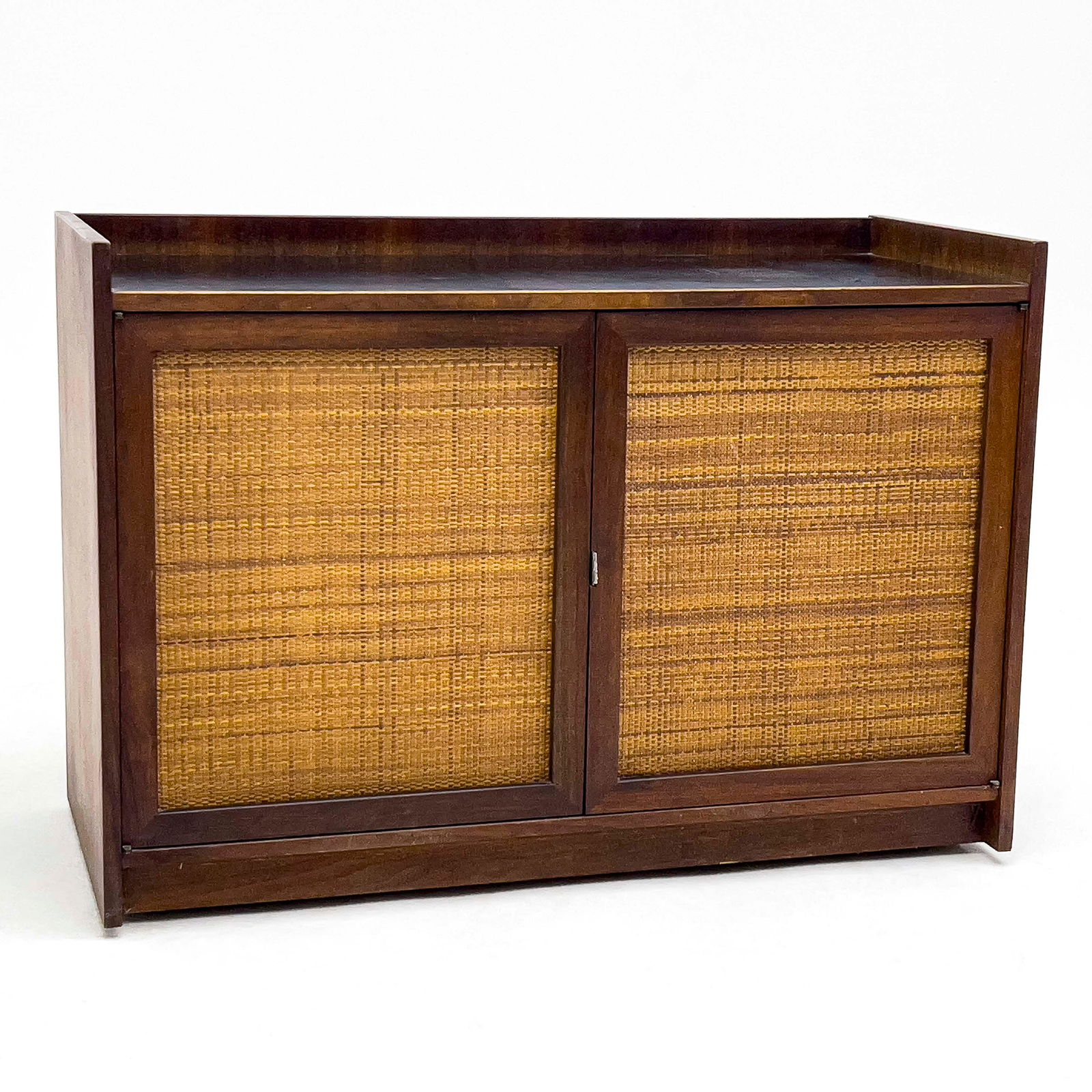 Jack Cartwright - Two-Door Cabinet: Lot 54 Jack Cartwright American (XX) Two-Door Cabinet (1960) walnut, cane, leather, and laminate two-door cabinet opening to storage and single drawer, raised on casters for Founders, USA 29 x 42 x 1