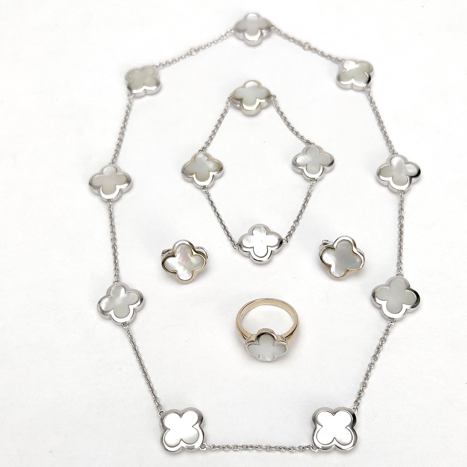 White Gold Quatrefoil Parure: Lot 40 White Gold Quatrefoil Parure 18k gold, mother of pearl Gold quatrefoil inset with mother of pearl parure comprising of a necklace, bracelet, matching earrings, and ring, each stamped 18k and 7