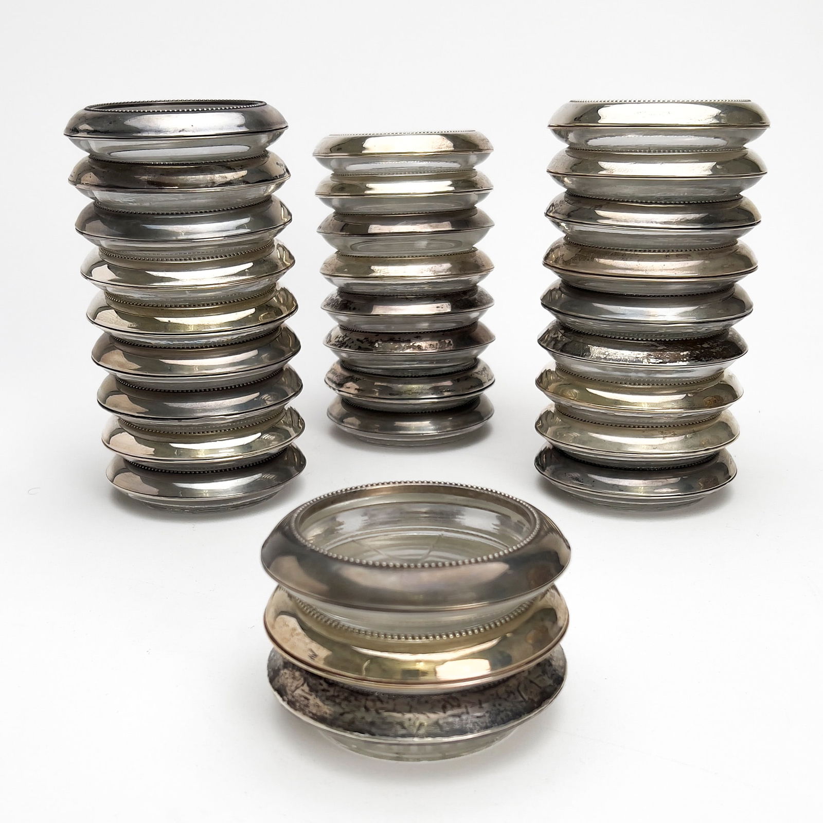Frank M. Whiting & Co. - Silver Mounted Glass Coasters, Group of 29: Lot 122 Frank M. Whiting & Co. American Manufacturer (Est. 1878) Silver Mounted Glass Coasters, Group of 29 sterling silver, glass Twenty-Nine sterling silver rim glass coasters with various cut