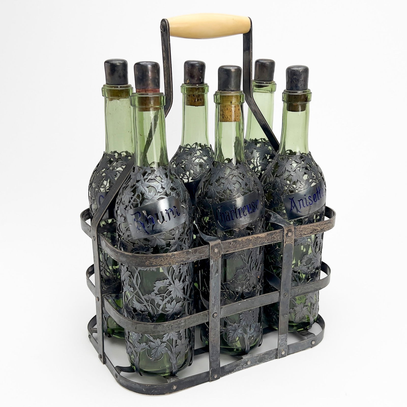 Enamel Silver Six Bottle Tantalus: Lot 251 Enamel Silver Six Bottle Tantalus A six bottle Tantalus, 6 green glass bottles with fine engraved and pierced silver covers with grapevine motif and rectangular labels for assorted liquors an