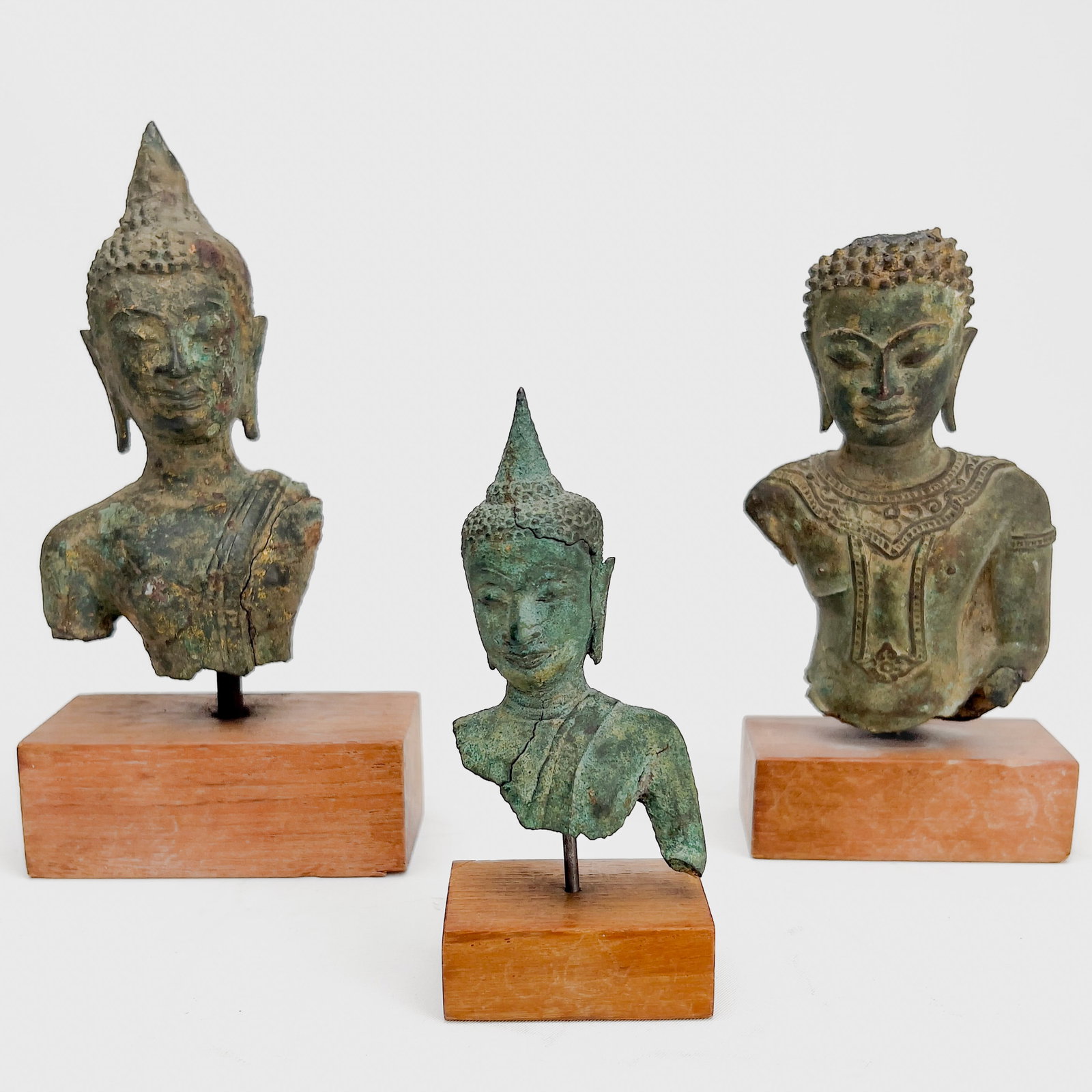 3 Small Buddha Bust Fragments On Stands: Lot 162 3 Small Buddha Bust Fragments On Stands bronze, teak largest: 5 inches largest with stand: 6 1/2 inches Description: A group of three Southeast Asian bronze Buddha busts featuring varying degr
