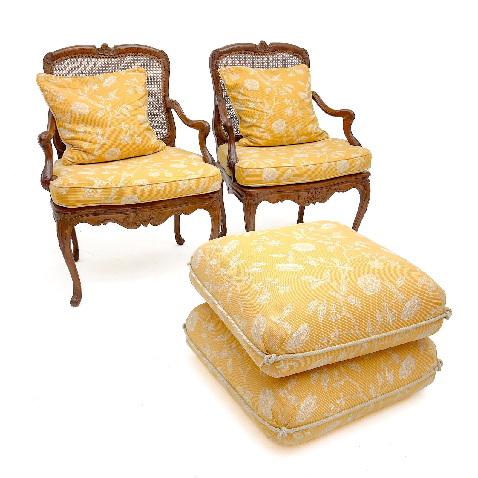 A Pair of 19th-Century French Louis XV Style Caned Bergères and a Contemporary Ottoman: Lot 215 A Pair of 19th-Century French Louis XV Style Caned Bergères and a Contemporary Ottoman Walnut, cane, fabric upholstery, foam padding 37 1/2 x 27 1/2 x 24 inches ottoman: 17 1/2 x 24 x 25 
