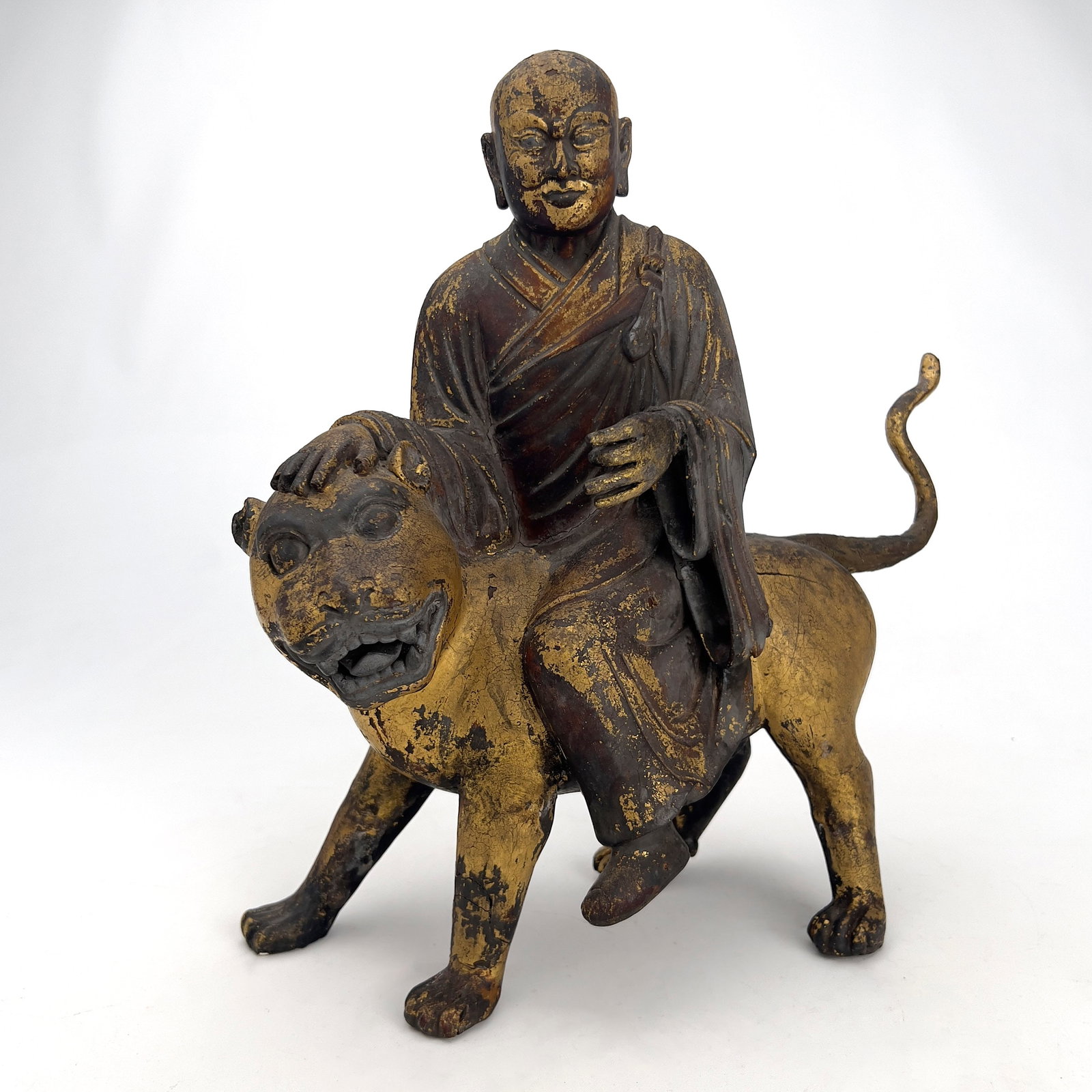 Chinese Polychrome and Parcel-Gilded Wood Figure of a Buddhist Arhat Riding a Lion: Lot 9 Chinese Polychrome and Parcel-Gilded Wood Figure of a Buddhist Arhat Riding a Lion (18th–19th Century) Wood, Plaster, Gold leaf, Pigment 14 1/4 x 14 x 6 inches Description: A Chinese parce