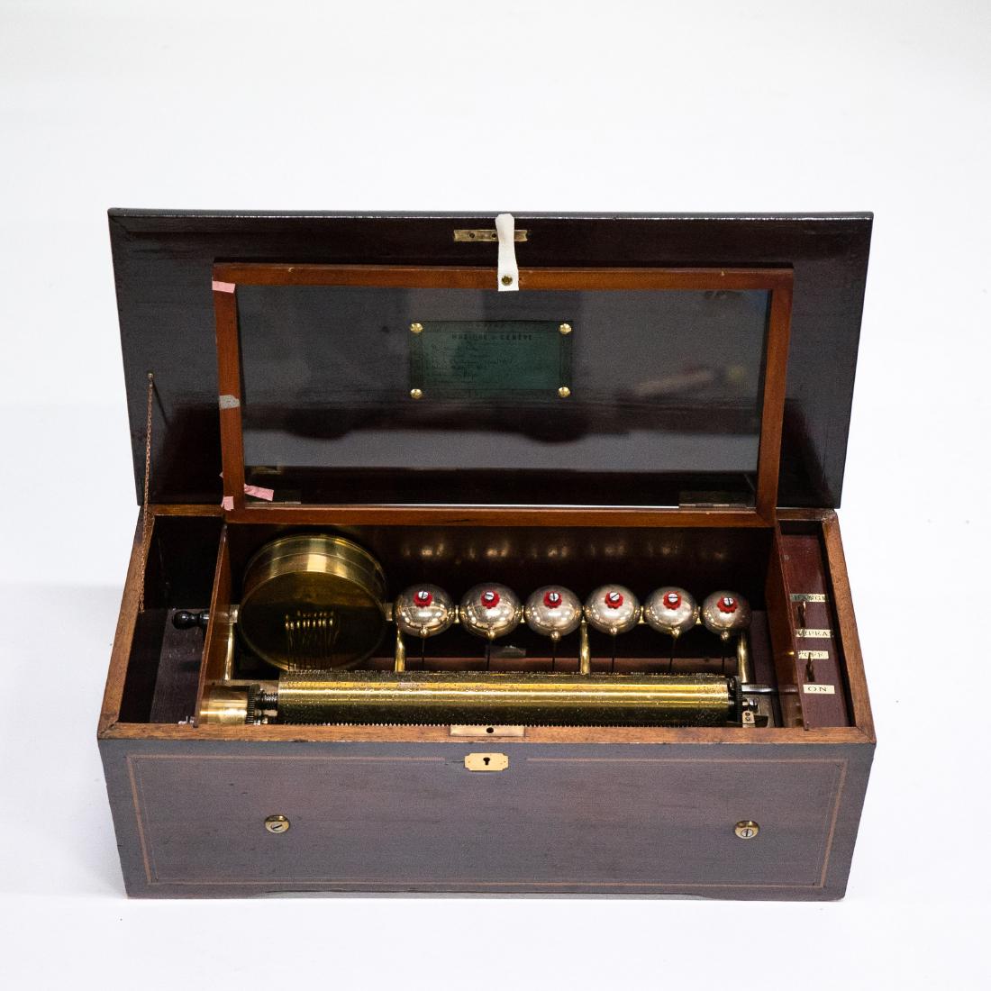 SWISS CYLINDRICAL MUSIC BOX WITH 6 BELLS & DRUM: Mahogany box with cherry lid containing inlaid wood designs. Mechanical music cylinder plays six old world tunes. Six bells, one hundred notes from cylinder, brass snare 5.5" drum with nine beaters, C