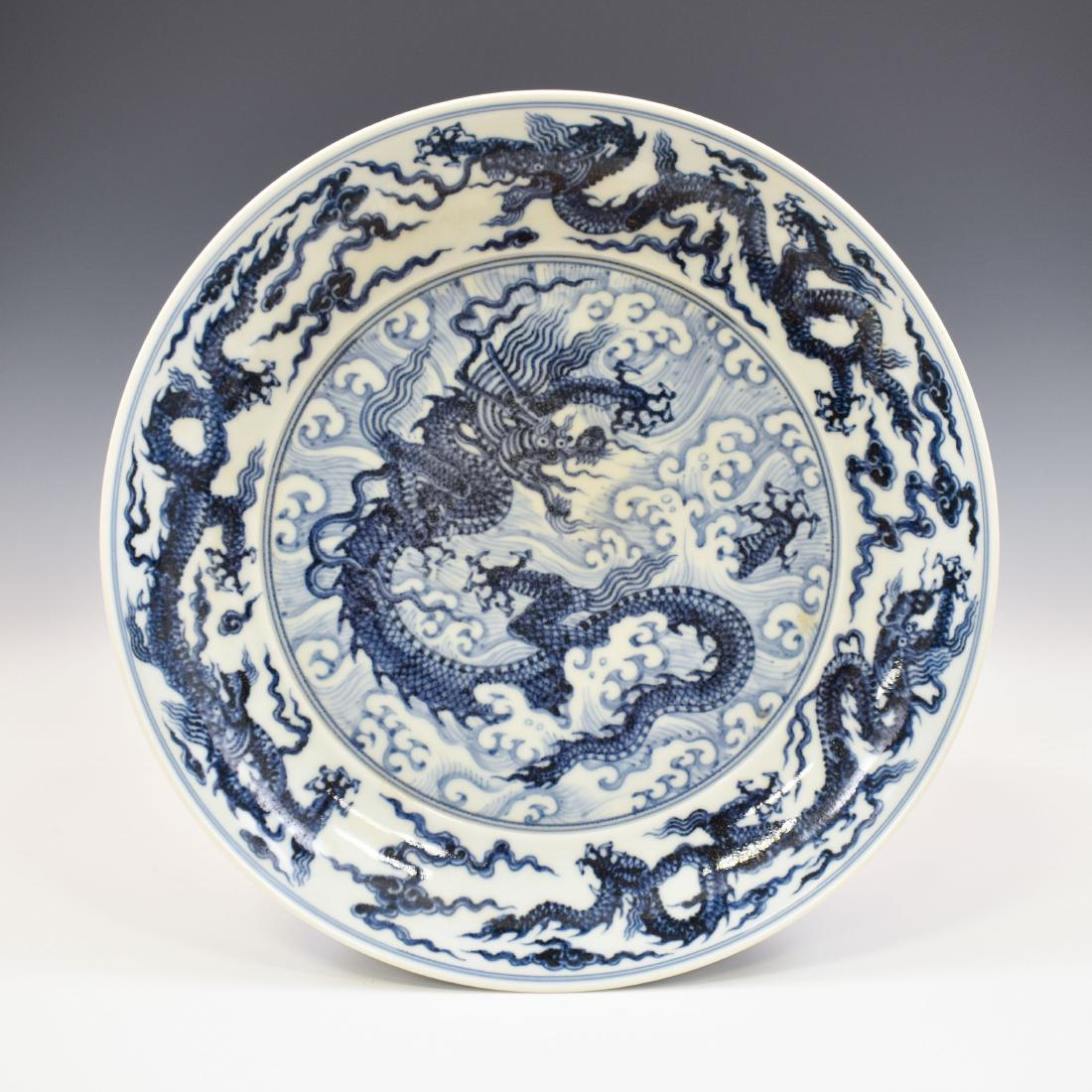 MING XUANDE BLUE & WHITE DRAGON PLATE: Chinese Ming Dynasty famous blue and white plate. The porcelain potted with a shallow body, of a shallow vessel, broad wide cavetto, with a slightly flared lip and shallow draft. All reserved in a cle