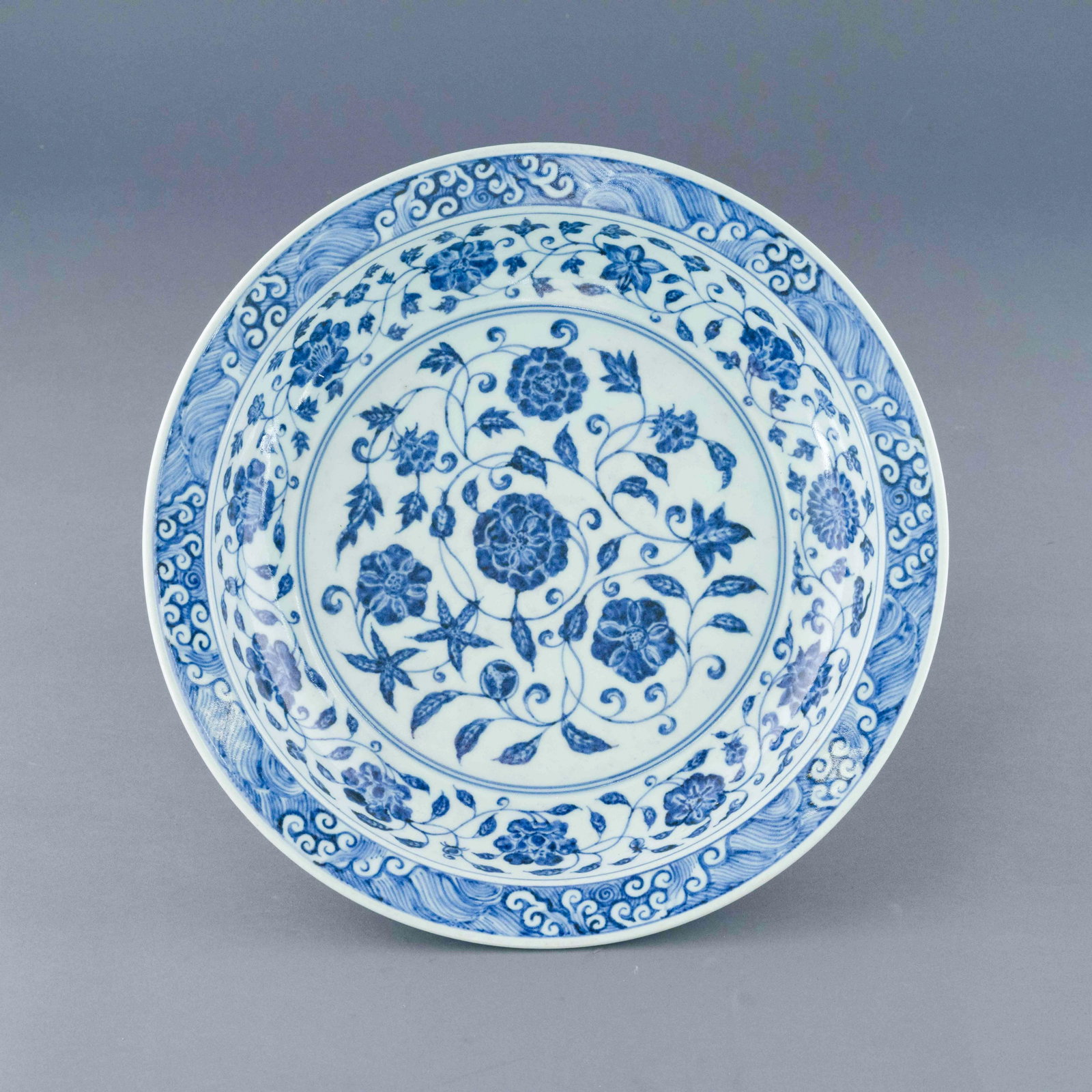 MING YONGLE BLUE AND WHITE FLORAL PLATE: Chinese Ming Dynasty Period, Yongle blue and white floral plate. The Porcelain potted in shallow vessel form, with broad wide central interior, rounded cavetto gently tapering to open wide, with strai