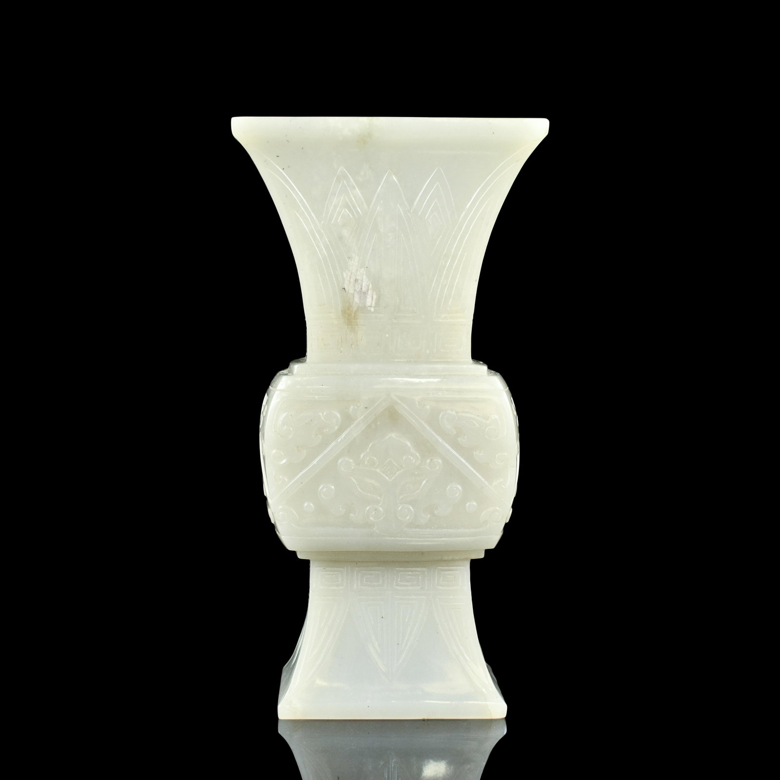 CHINESE JADE CARVED GU VASE: Measurements: Height: 6 1/4" Width: 3 1/4" Weight: 309 g Chinese jade carved gu vase. Squared body with a flared opening and splayed foot base. Exterior carved with tropical leaves banded on the neck 