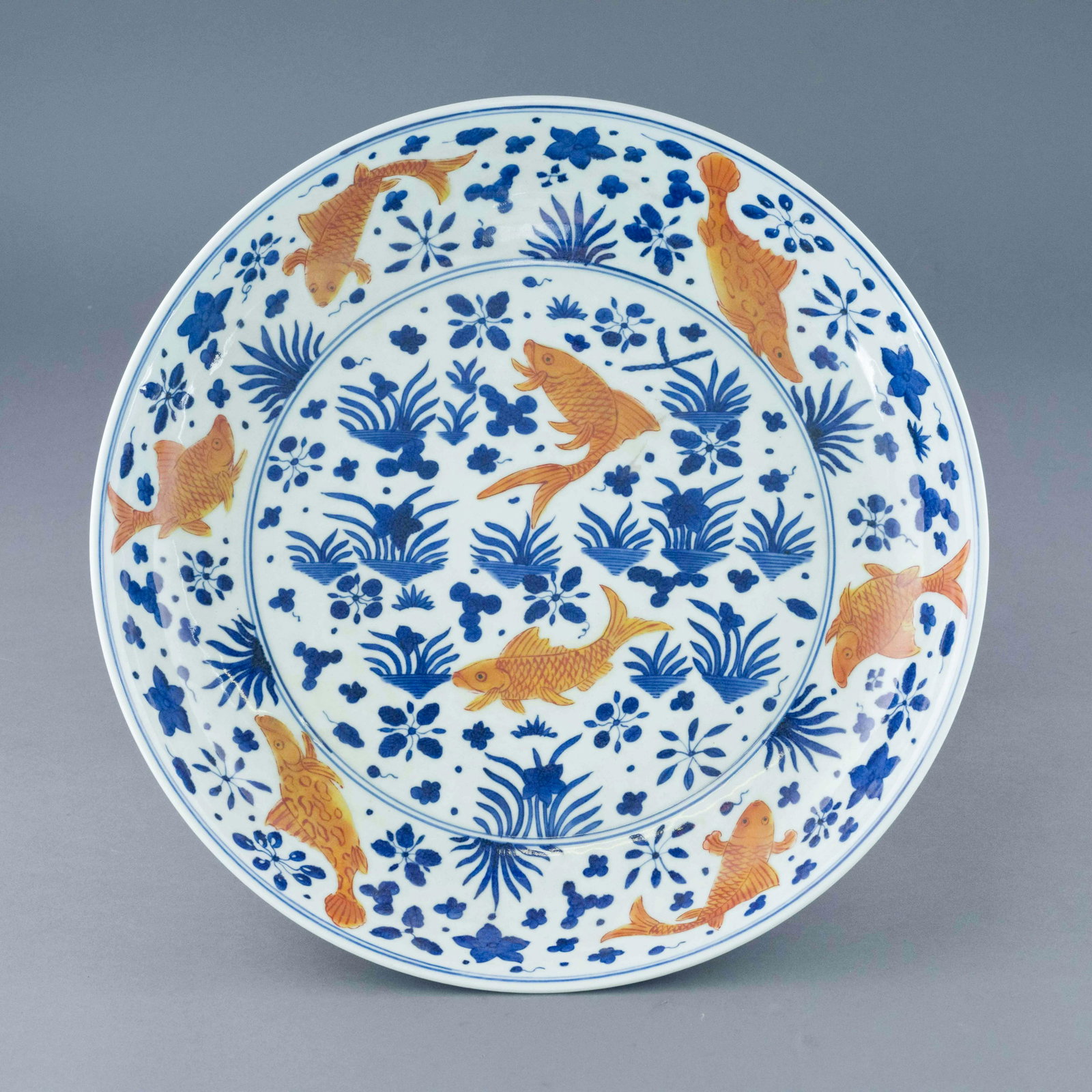 MING BLUE AND RED CARPS PLATE: Measurements: 3in H x 17.75in W x 17.75in D Chinese Ming Dynasty Period, blue and red carps plate. The Porcelain potted in shallow vessel form, with broad wide central interior, rounded cavetto gently