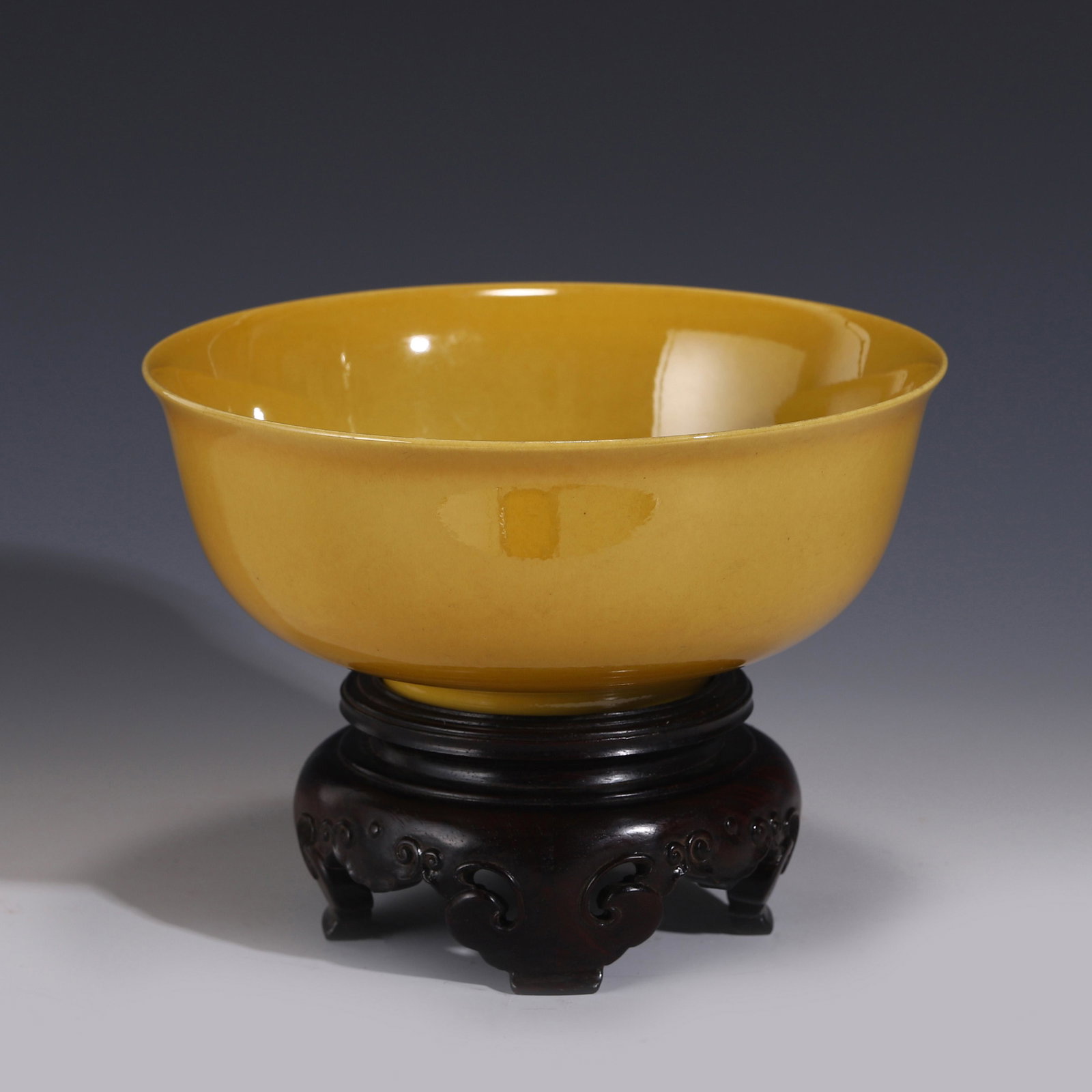 YELLOW GLAZE MONOCHROME BOWL ON STAND: Measurements: Height: 8 cm Diam: 20 cm Chinese Ming Dynasty Period, Hongzhi Yellow Glazed Monochrome Porcelain Bowl on Carved Wooden stand. Potted with a shallow body, has an open mouth, slight flarin