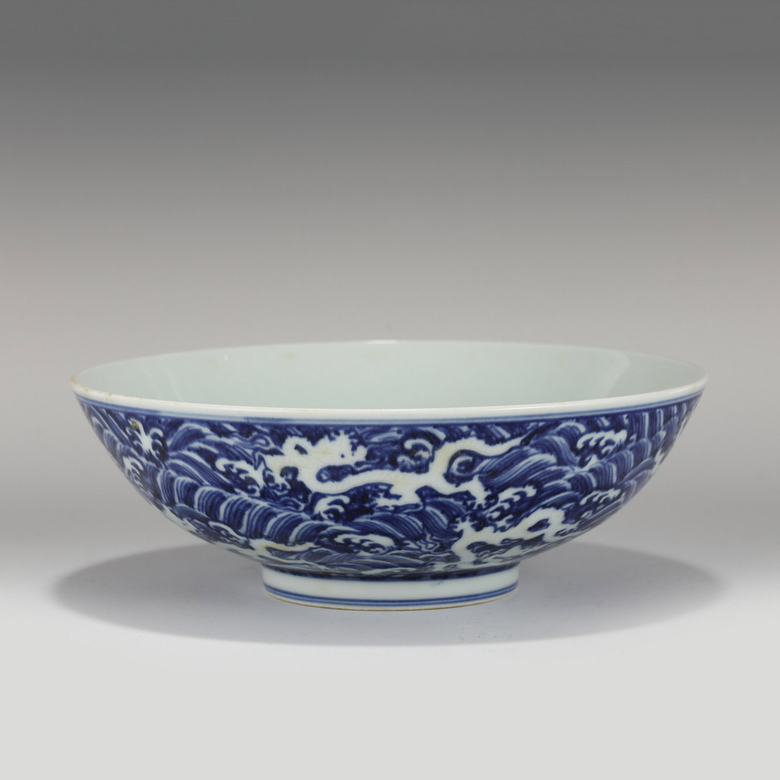 XUANDE BLUE & WHITE DRAGON PORCELAIN BOWL: Measurements: Height: 8.8 cm, Diam.: 26 cm Chinese Ming Dynasty XuanDe Blue & White Dragon Motif Porcelain Bowl. The bowl has an open mouth, rounded lip rim, thick, deep arced body, raised with round 