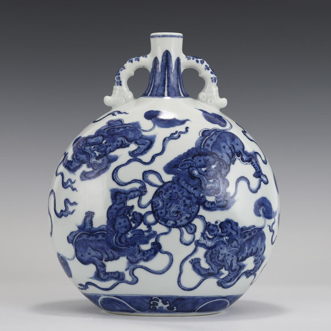 QING BLUE & WHITE FU DOGS MOON FLASK: PROVENANCE: Saint Matthew, Kentucky Private Collector. Measurements: Height: 30 cm, Length: 24 cm, Width: 15cm Chinese Qing Blue & White Fu Dogs and Silk-Ball Motif Porcelain Moon Flask, Qianlong Mark