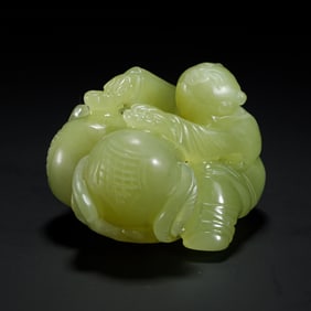 YELLOW JADE CARVING OF A CHILD WITH A PEACH - LIKE OBJECT