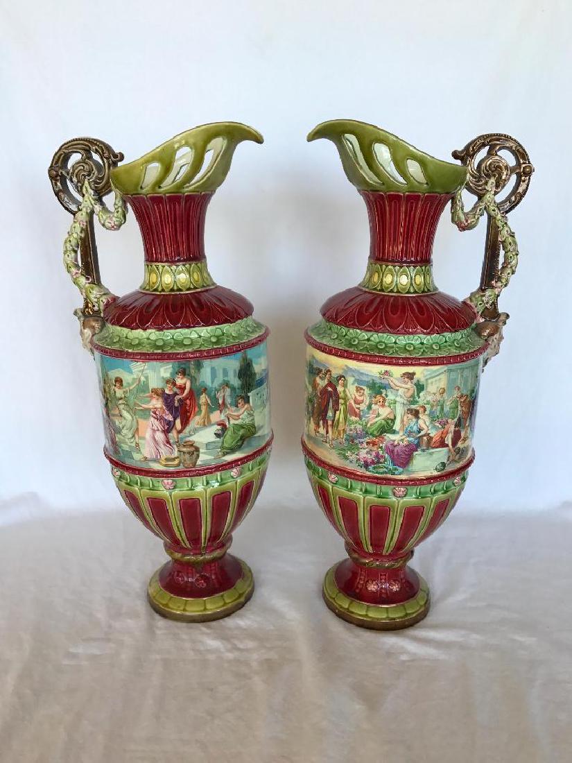 Pair of Large French Majolica Ewers, 19th Century: Pair of large 19th century French majolica ewers. Urn shaped with pierced handles, each finely decorated with garlands of flowers and bacchanal mask. Very finely detailed scene, a different one on eac