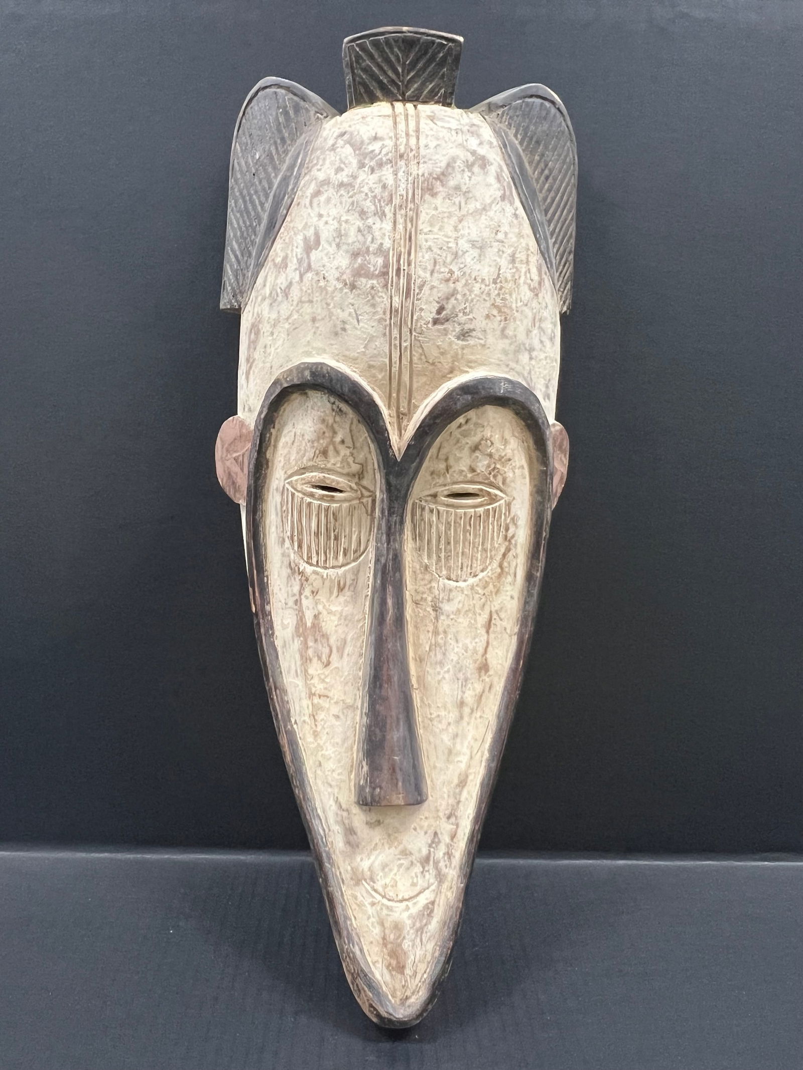 Fang Mask: African Tribal Art Carved Wood Fang Mask. The dimension is 23 inches high x 9 inches wide. Please be aware that some of the items are vintage, secondhand, old ages, antiques and may have a defects or