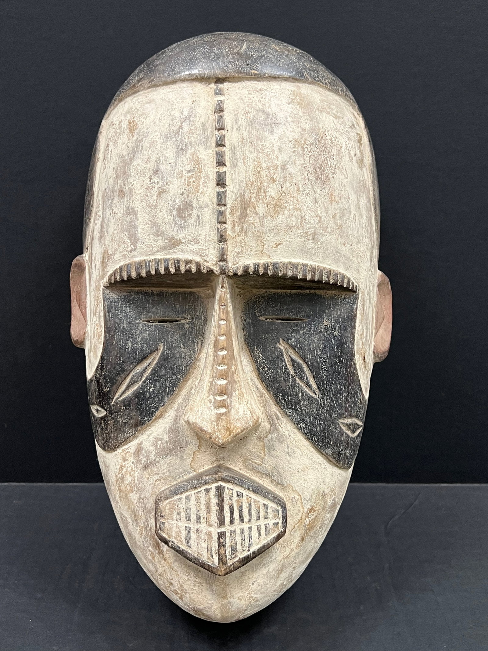 Carved Wood Ibo Mask: African Tribal Art Carved Wood Ibo Mask. The dimension is 16 inches high x 10 inches wide. Please be aware that some of the items are vintage, secondhand, old ages, antiques and may have a defects or
