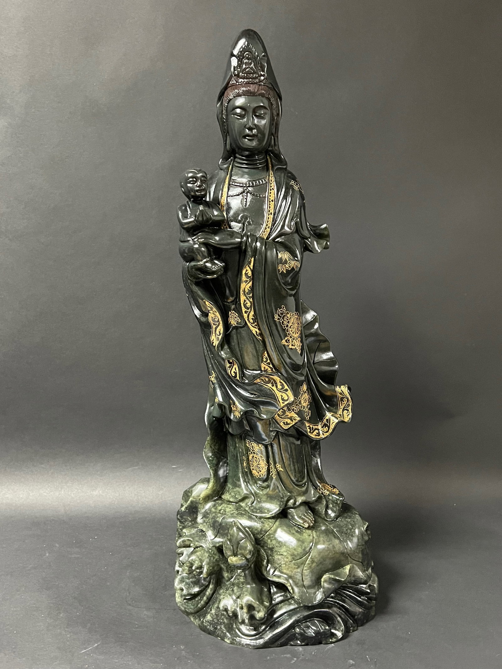 Carved Dark Green Shoushan Stone Quanyin Holding Baby Sculpture with Gold Accent: Chinese Art Carved Dark Shoushan Stone Quanyin Holding Baby Sculpture with Gold Accent. The dimension is 23.5 inches high x 9 inches wide. Please be aware that some of the items are vintage, secondhan
