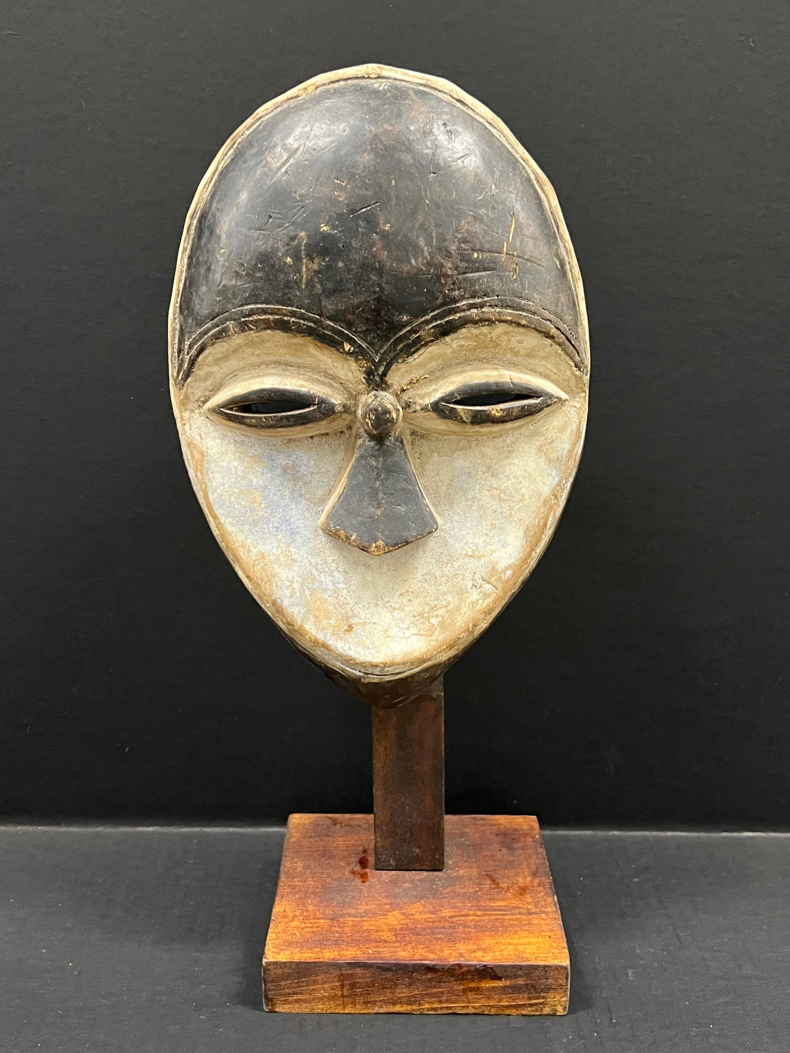 Carved Wood Kwele Mask with Display Stand: African Tribal Art Carved Wood Kwele Mask with Display Stand. The dimension is 17 inches high x 8 inches wide. Please be aware that some of the items are vintage, secondhand, old ages, antiques and