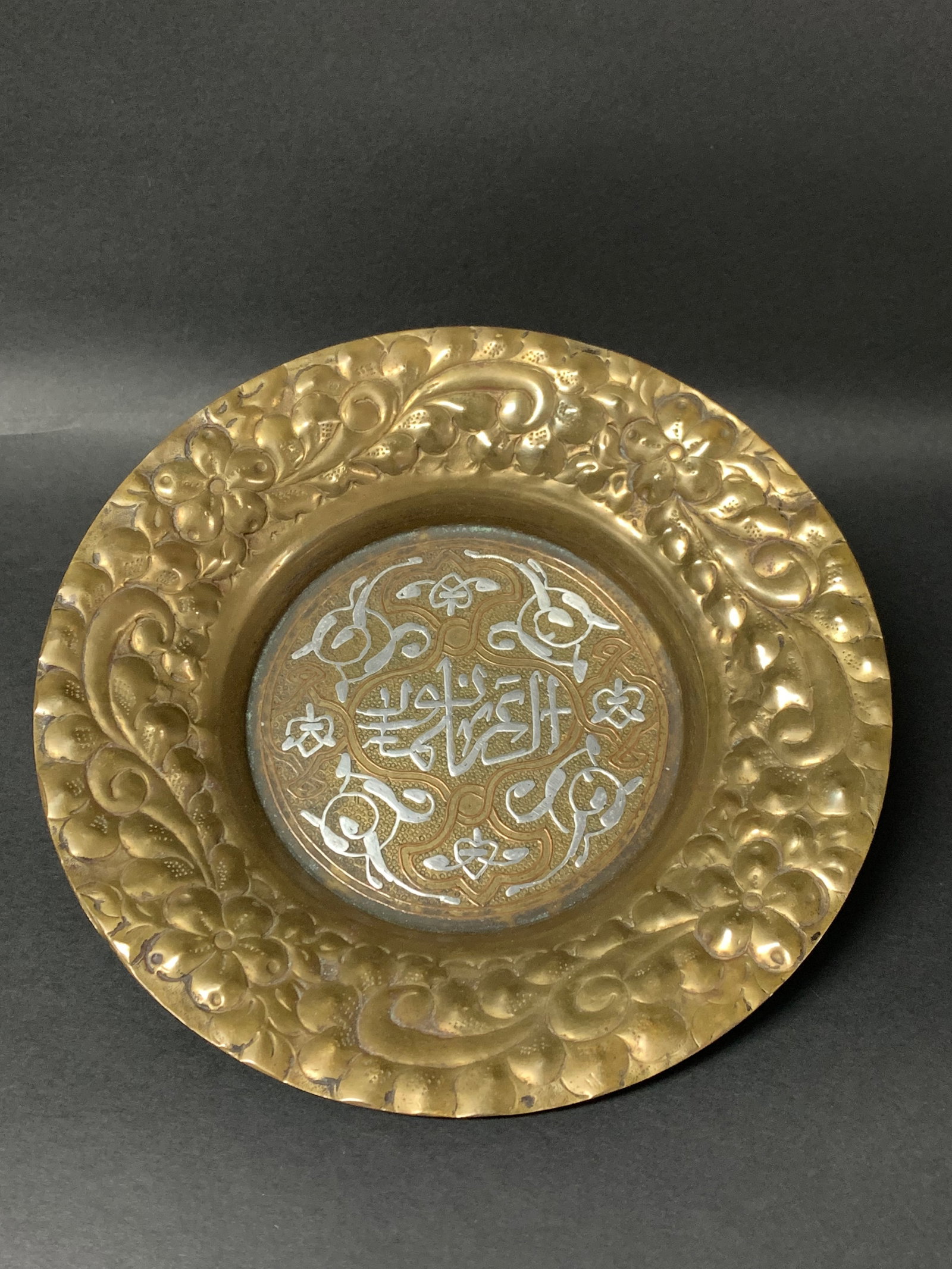 Vintage Middle Eastern Brass Plate with Silver Arabic Calligraphy Inlays: Vintage Middle Eastern Brass Plate with Silver Arabic Calligraphy Inlays. The dimension is 8.75 inches high x 8.75 inches . Please be aware that some of the items are vintage, secondhand, old ages, an