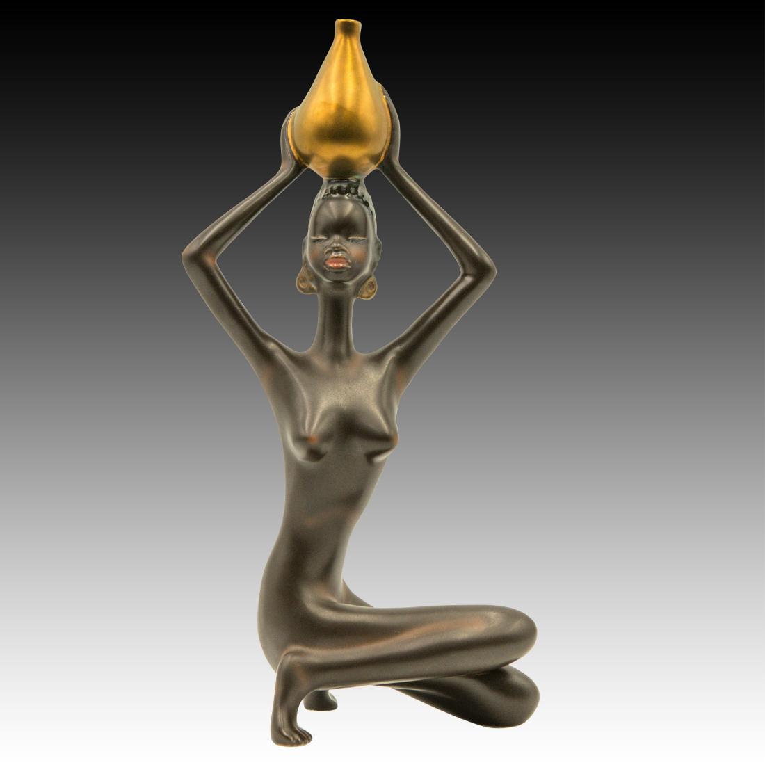 Goebel Zulu Young Woman Water Carrier Figurine: Goebel Zulu Young Woman Water Carrier Figurine A Goebel Ebony figurine, of a young Zulu woman balancing a ceramic jar of water on her head. Trademark 6, or made 1980 - 1992. Round foil Goebel W. Germa
