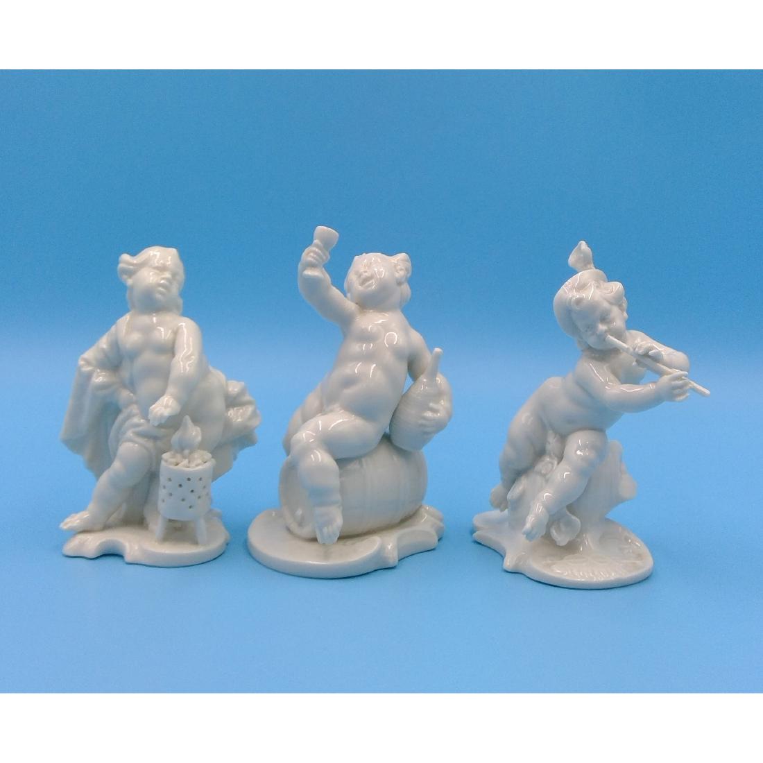 GROUP OF 3 NYMPHENBURG CHERUB FIGURINES: Group of 3 Nymphenburg Blanc de Chine Porcelain Figurines designed by Franz Anton Bustelli: cherub playing flute, drinking wine and cherub by the fire. Circa early 20th century. Model numbers 241, 267
