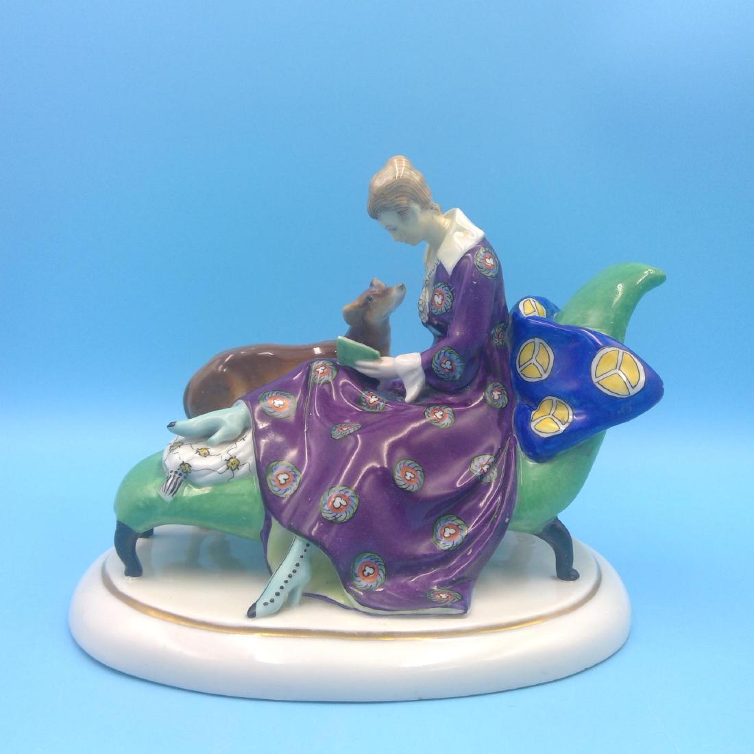 GOEBEL ART DECO GERMAN PORCELAIN FIGURINE: Goebel Art Deco Figurine of a Lady Reading a Book on the Couch with her Dog by the side. Circa 1923-1949. ; Country of Origin: Germany; Dimensions: 8"L x 6.5"H x 6"W;