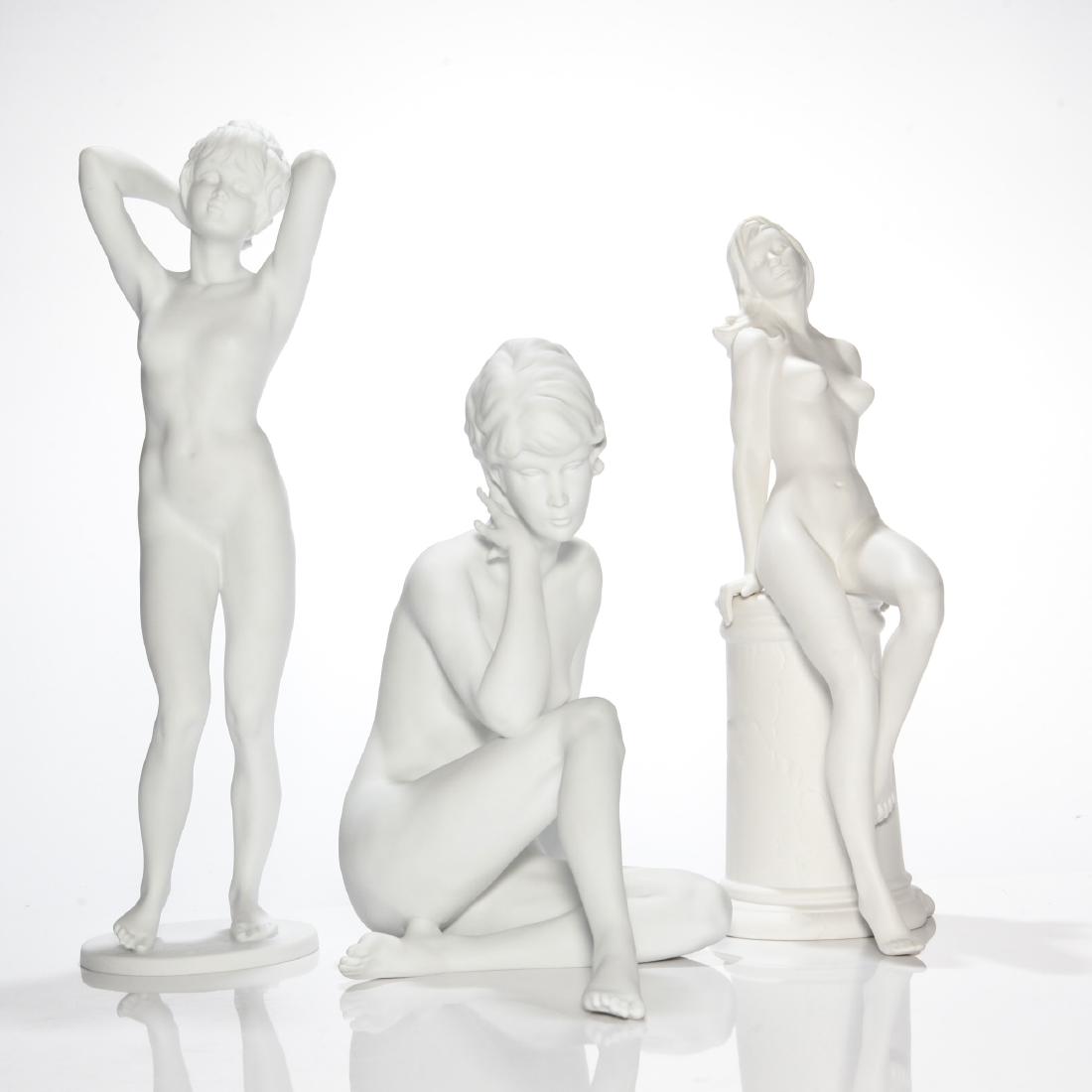 GROUP OF 3 GERMAN PORCELAIN NUDE FIGURINES: Group of 3 Figures: 1) Goebel Lady Leaning on the Column (10.5"H x 5.5"L x 4"W). Model number 1302528. 2) Kaiser Seated Nude (9"H x 8"L x 7"W). Model number 489. 3) Kaiser Nude Lady Fixing Her Hair (1
