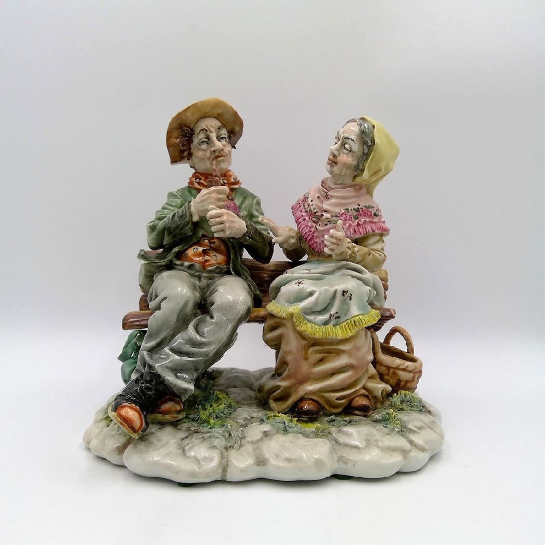 ANTIQUE CAPODIMONTE LARGE PORCELAIN GROUP FIGURINE: Capodimonte Figurine of a Couple Sitting on the Bench. Circa early 20th century. Country of Origin: Italy; Dimensions: 8"H x 8"L x 7"W;