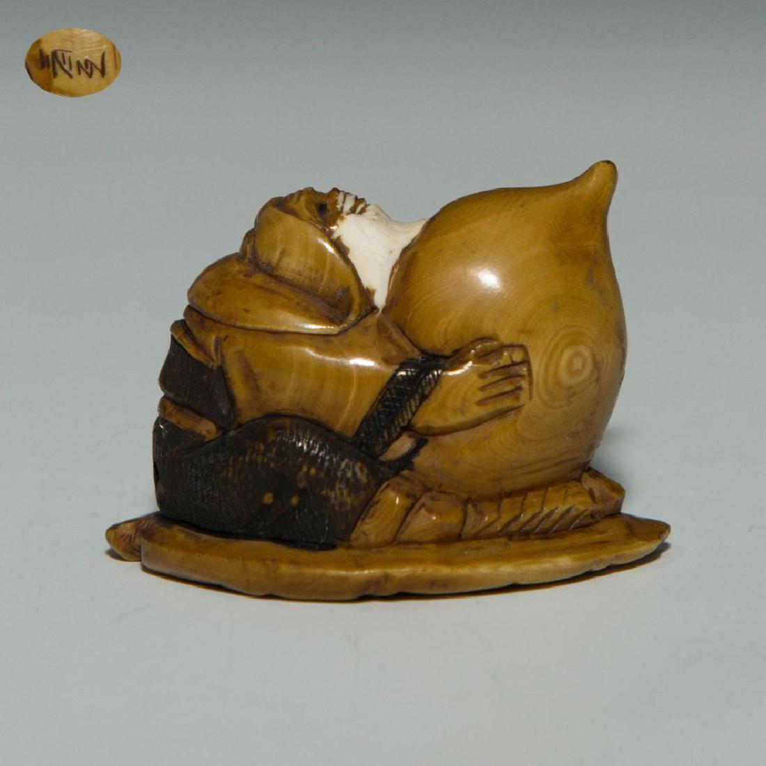 ANTIQUE JAPANESE CARVED BONE NETSUKE MAN WITH PEACH: Netsuke carving of a man sitting on a leaf with a giant peach. Inscribed signature on the bottom. Dimensions: almost 2"L Country of Origin: Japan