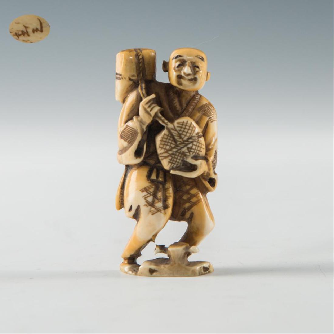 ANTIQUE JAPANESE CARVED BONE NETSUKE MAN: Netsuke carving figure of a man carrying two bags. Inscribed signature on the bottom. Dimensions: 2.25"H Country of Origin: Japan