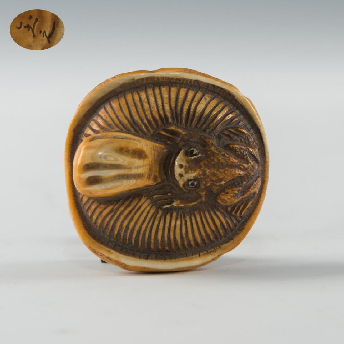 ANTIQUE JAPANESE CARVED BONE NETSUKE FROG ON MUSHROOM: Netsuke carving figure as a frog sitting on a mushroom. Inscribed signature on the bottom. Dimensions: 1.5"D Country of Origin: Japan