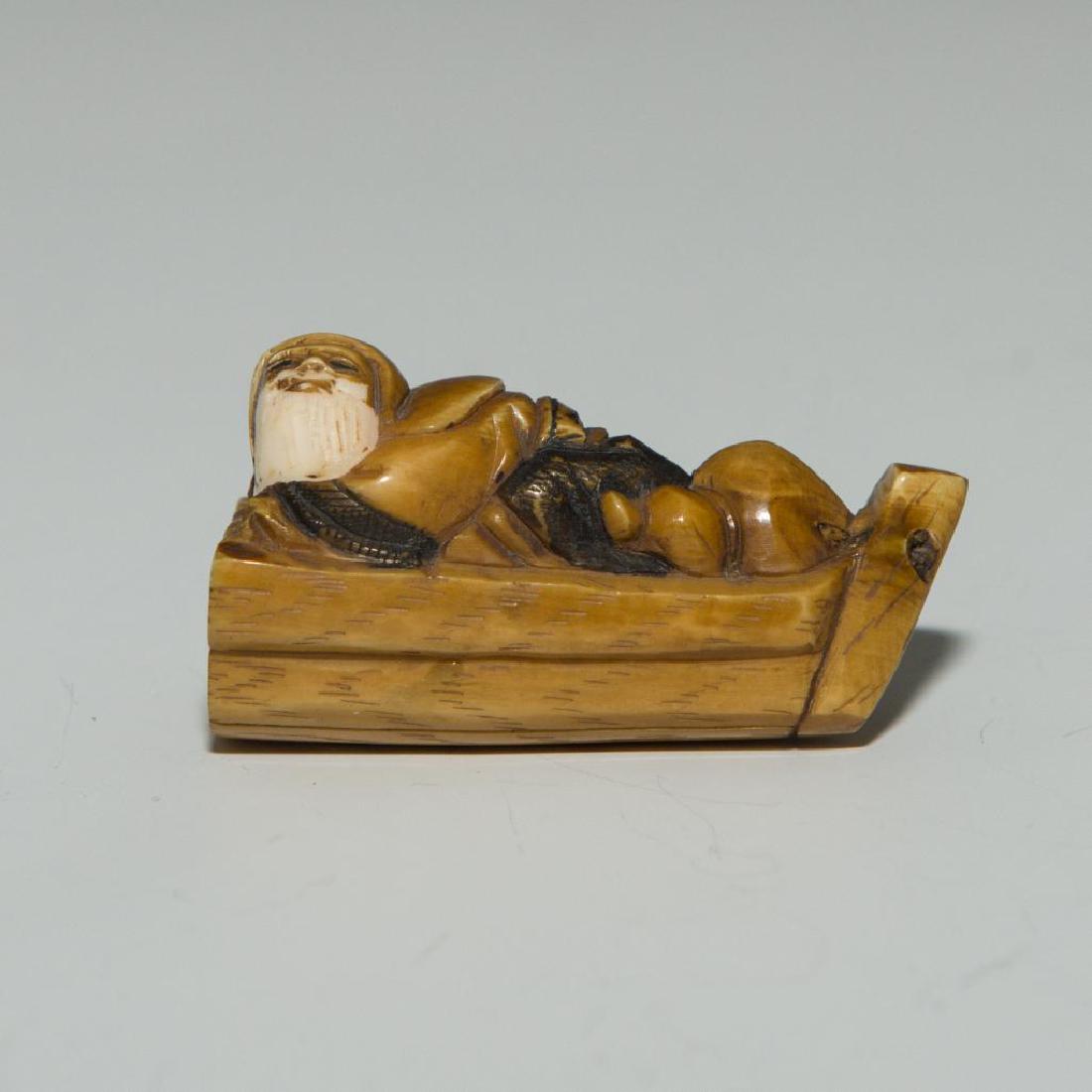 ANTIQUE JAPANESE CARVED BONE NETSUKE MAN ON BOAT: Netsuke carving figure as a man on boat. Dimensions: 2"L Country of Origin: Japan