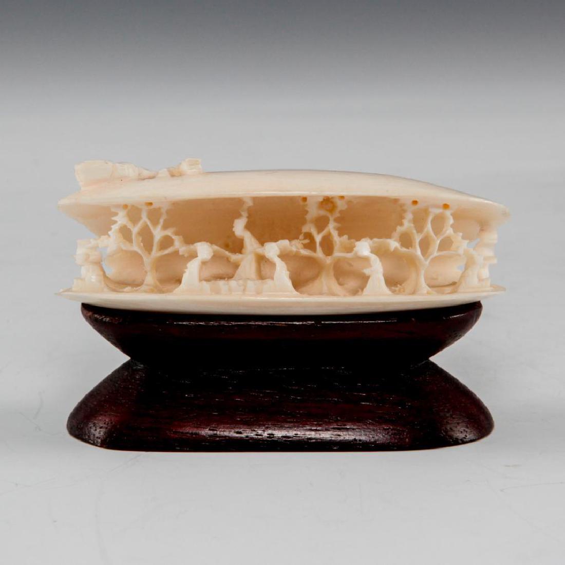 ANTIQUE CHINESE CARVED BONE FIGURE VILLAGE IN A SHELL: Fine carving in shape of a mussel shell. Depicts village inside and fish on top. Comes with a wood stand. Dimensions: 2.5"L