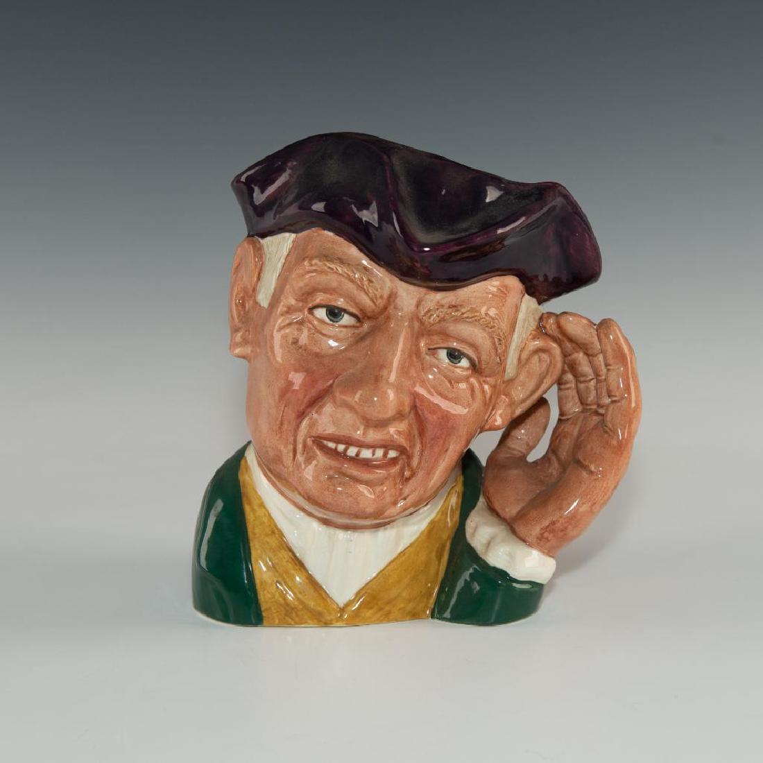 ROYAL DOULTON CHARACTER JUG 'ARD OF 'EARING: Model D6588 Depicted with dark purple tricorn; green, white and yellow clothing. "With hand held to cup his ear, this cockney gentleman is a comic representation of a deaf man. After being discontinue