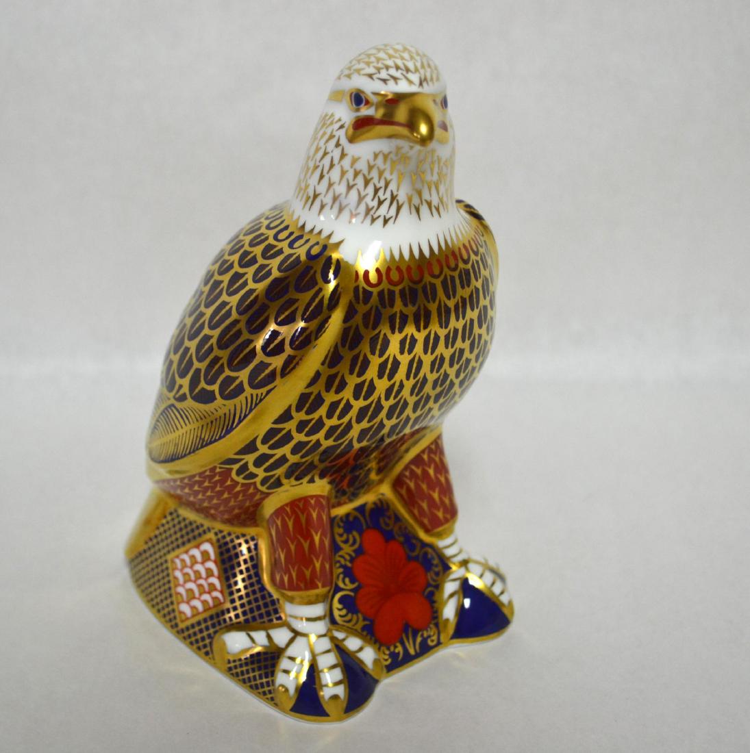 ROYAL CROWN DERBY EAGLE FIGURINE: Fine Bone China. Gold Button/Plug. Signed by Sir Michael Doulton. Glazed Porcelain Decorated. Applied Gold accents, Cobalt Blue with Terra Cottal Variations. HM: LXI. Dimensions: 7" H x 3 1/2" W x 5" 