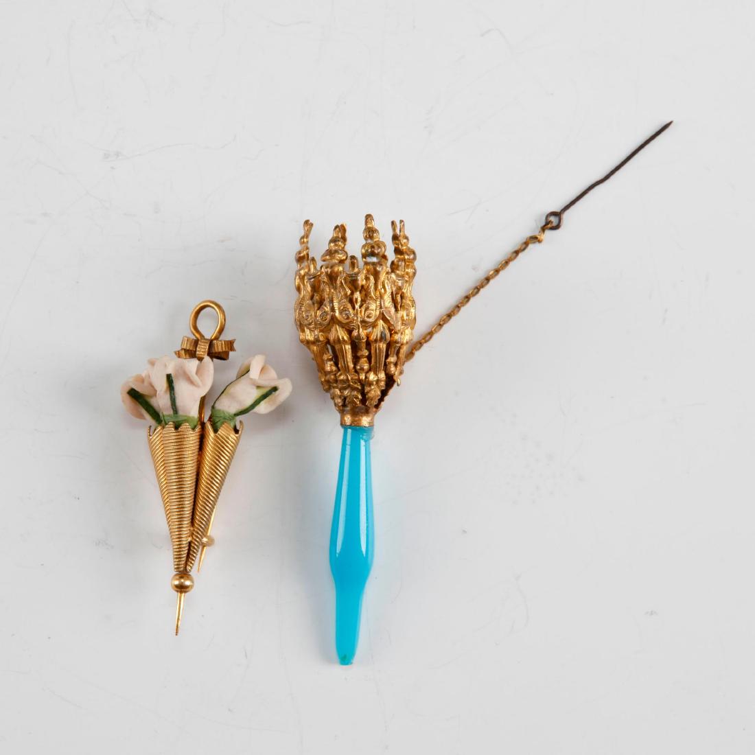 PAIR OF ANTIQUE ENGLISH VICTORIAN GOLD POSEY PINS: Gilt floral posey Boutonniere lapel pin. Includes embossed posey holder with teal-blue glass handle and pin with chain; 3.25"H. Vase-shaped posey holder with ribbon and standard back pin and hook; 2.5