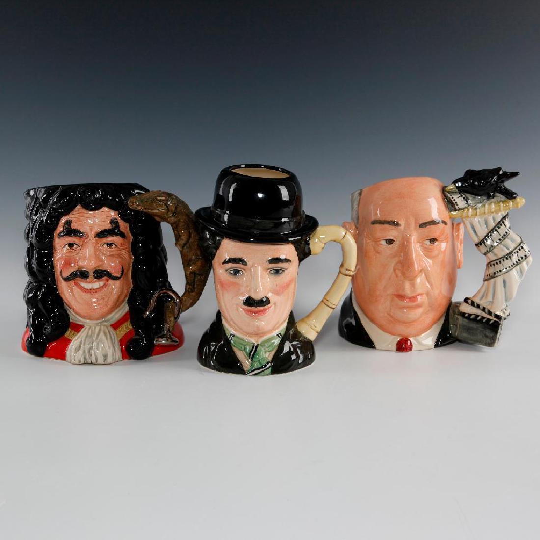 SET OF 3 ROYAL DOULTON LARGE CHARACTER JUGS: Jug depicts famous people from the movie industry. Charlie Chaplin D6949, Captain Hook D6947 and Alfred Hitchcock D6987.Tallest: 7.25"H. Artist: Various Issued: late 20th century Manufacturer: Royal D