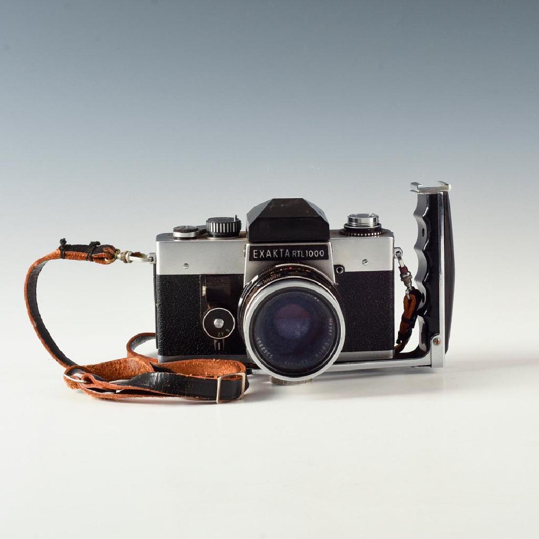 VINTAGE EXAKTA RTL1000 GERMAN SLR CAMERA WITH STRAP: Flash/accessory press handle attached; Meyer 1.8 F50mm lens. Dimensions: 7"L X 4"D X 5"H Manufacturer: Ihagee Country of Origin: Germany