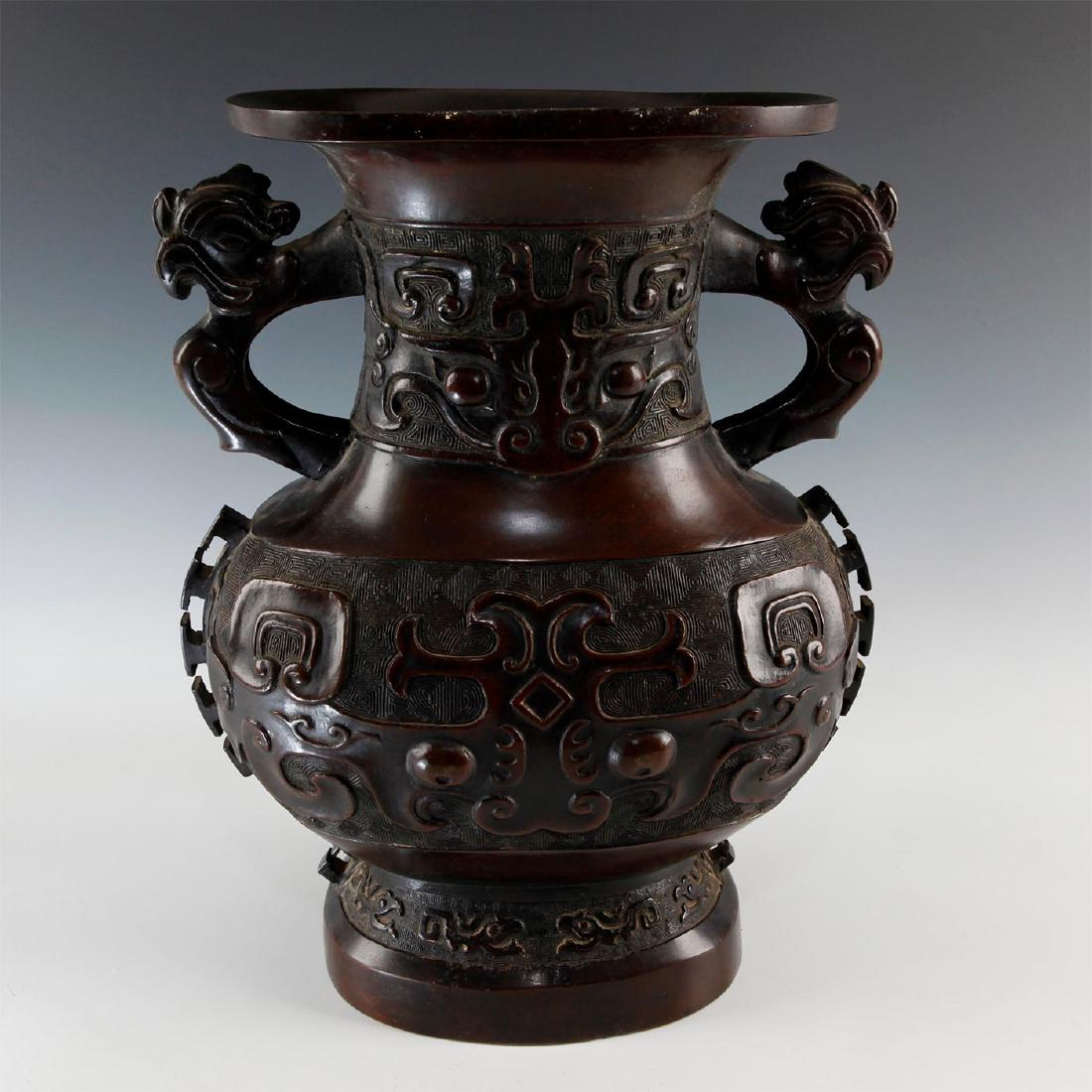 CHINESE IMPRESSIVE BRONZE HU SHAPED VESSEL WITH HANDLES: Ellipse shaped vessel with large open mouth and bulbous gourd body on footed base decorated in Buddhist symbols and shapes. The handles are cockerels shapes with bands of decoration on neck, mid secti