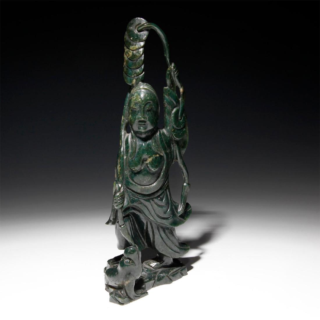 CHINESE CARVED JADE FIGURAL STUDY GUANYIN AND BABY: Striking dark green jade. Carved into a likeness of a Chinese divinity holding various ceremonial implements, with a baby at her feet. Issued: 19th-20th century Dimensions: 11.75"H Country of Origin: 