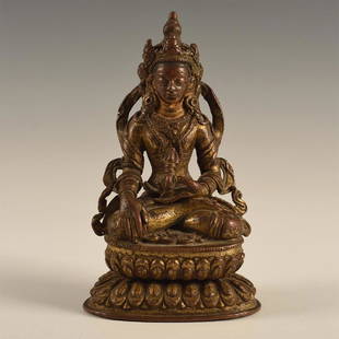 CHINO-TIBETAN GILDED BRONZE CROWNED BUDDHA: Seated cross legged on a double lotus, in front of stele, holding Bajra. Dimensions: 5.75"H X 3.5"D Country of Origin: Sino-Tibet