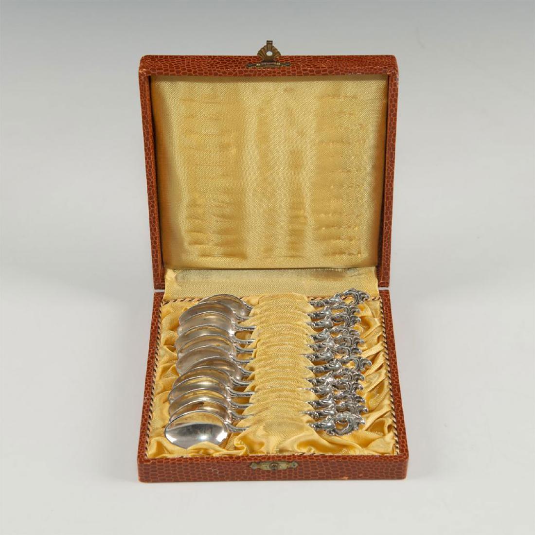 BOXED SET OF 12 ORNATE 800 SILVER GERMAN TEASPOONS: Yellow satin lined box; flower-stem motif handles; 5.44 troy. Post-1880s crescent and crown national German stamp and 800 impressed on bottoms. Dimensions: 5.5"L X 5.5"D x 1.25"H Country of Origin: Ge