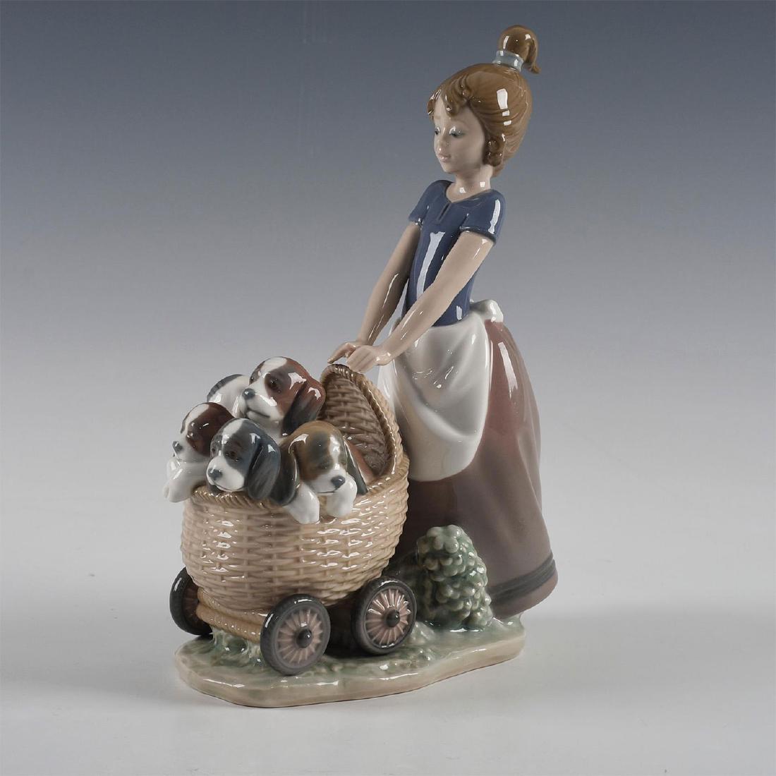 LLADRO FIGURINE LITTER OF FUN: Figure of girl with stroller filled with puppies - Lladro number 01005364. Lladro backstamp. Artist: Jose Roig Issued: 1986 Dimensions: 8.5"H Manufacturer: Lladro Country of Origin: Spain