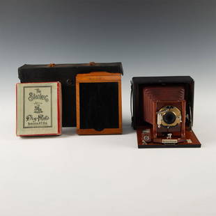 MAHOGANY ANTIQUE PLATE CAMERA IN CASE WITH UNUSED FILM: Case includes pack of plates, wood plate holder, and camera. Pack of Stanley brand 4x5 dry plates (opened), Seroco folding camera in brass, mahogany, and cordovan leather, and a wooden plate holder. 