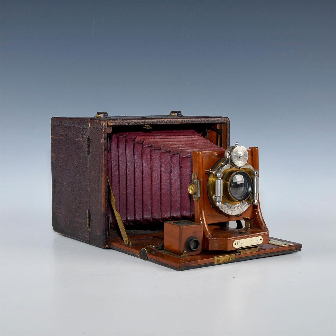 UNIQUE HIDDEN COMPARTMENT ANTIQUE WOOD FOLDING CAMERA: Hatch reveals hidden glass and film pack; red leather bellows. Unicum shutter, Poco B model. Issued: 1900s Dimensions: 10.25"L x 7"D x 5.5"H, open Manufacturer: Poco Country of Origin: United States