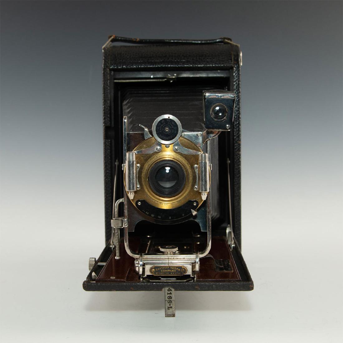 KODAK NO. 4A FOLDING CAMERA: Large black folding camera with mahogany wood on the inside. Bellows of the camera are in good cosmetic condition. Has Bausch and Lomb lens, with brass front fitting. Issued: 1916-1920 Dimensions: 10.
