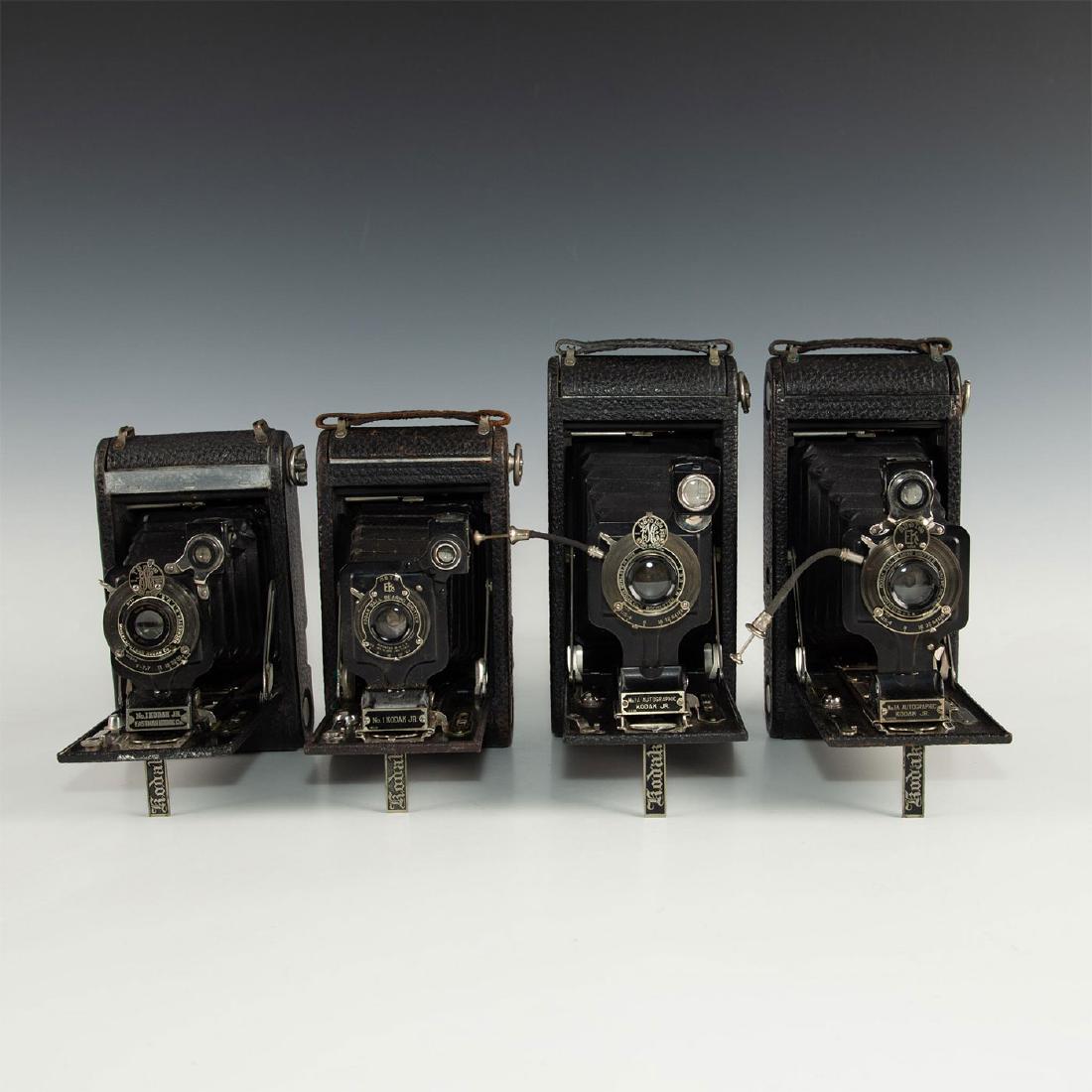 GROUP OF 4 VINTAGE KODAK JUNIOR FOLDING BELLOWS CAMERAS: Black leatherette exterior with chrome and other pieces. Grouped for decorative appeal, four Kodak Model 1A Autographic Junior cameras, two with the name AUTOGRAPHIC on front plate, two without (the o