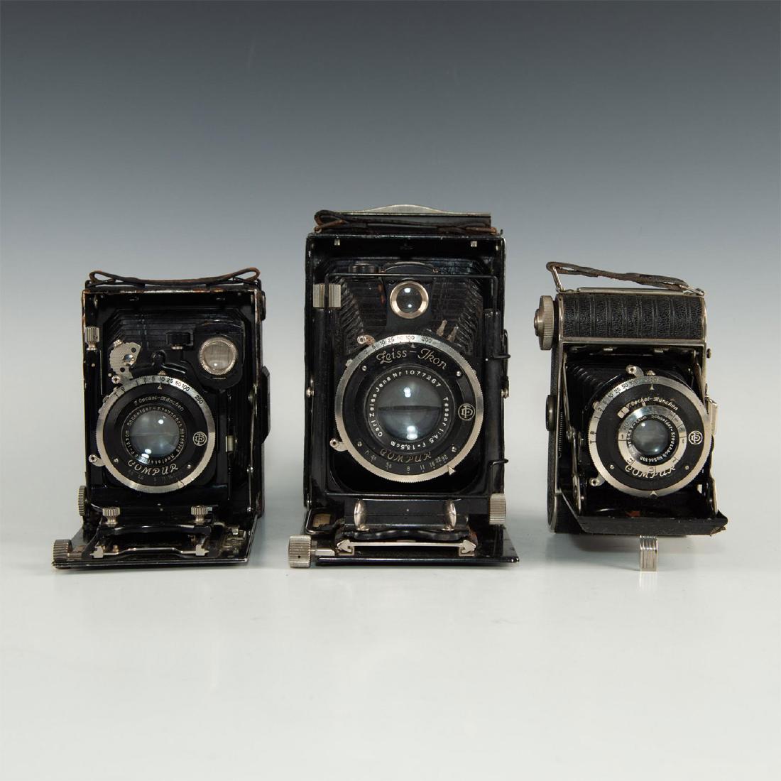 GROUP OF 3 VINTAGE ZEISS IKON FOLDING CAMERAS: Antique trio of German roll film cameras replete with chrome and leatherette. The medium and larger cameras function mechanically but speeds and full functions remain untested; one is a Bee Bee model.