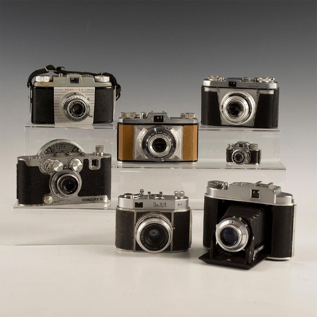 GROUP OF 7 VINTAGE MID-CENTURY CAMERAS: Group of 7 viewfinder cameras. Unique for collectors. Including: Mercury II, Bolsey, Kodak Pony 135, Franka Solida II, Dejur D-1, Iloca Rapid, and a mini Kassin spy camera. Issued: Early 20th c. Dimen