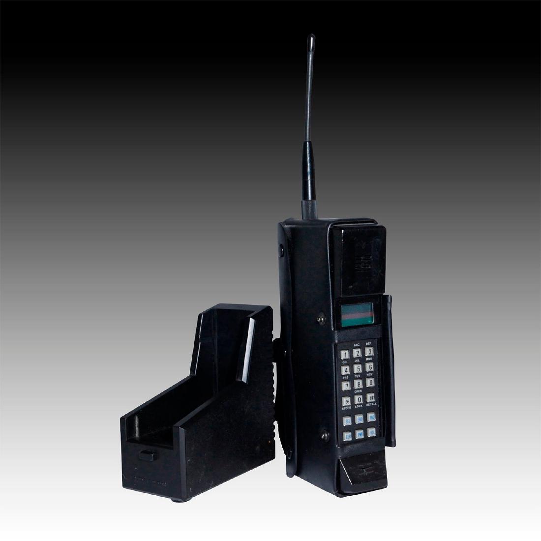 RADIO SHACK CELLULAR PHONE IN CASE: A Tandy Radio Shack Model CT-301 mobile phone with base charger. Black metal and other materials, original antenna, and stylish soft black carry case with hand strap and numerous locking snaps. Issued